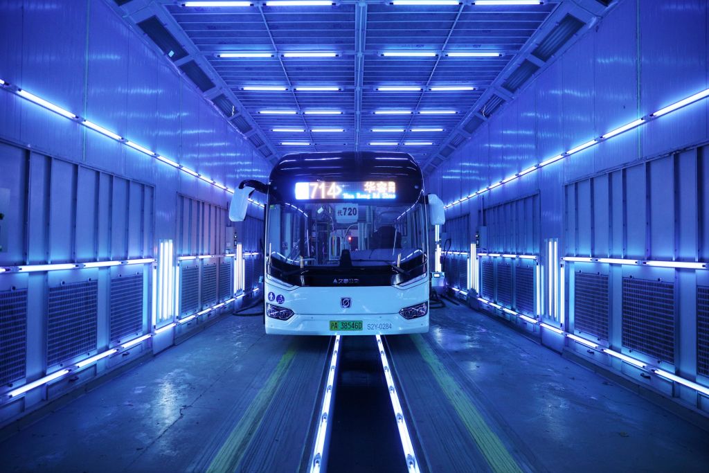 Decontaminated bus Photograph of an empty bus in a tunnel surrounded by lamps that are glowing violet.