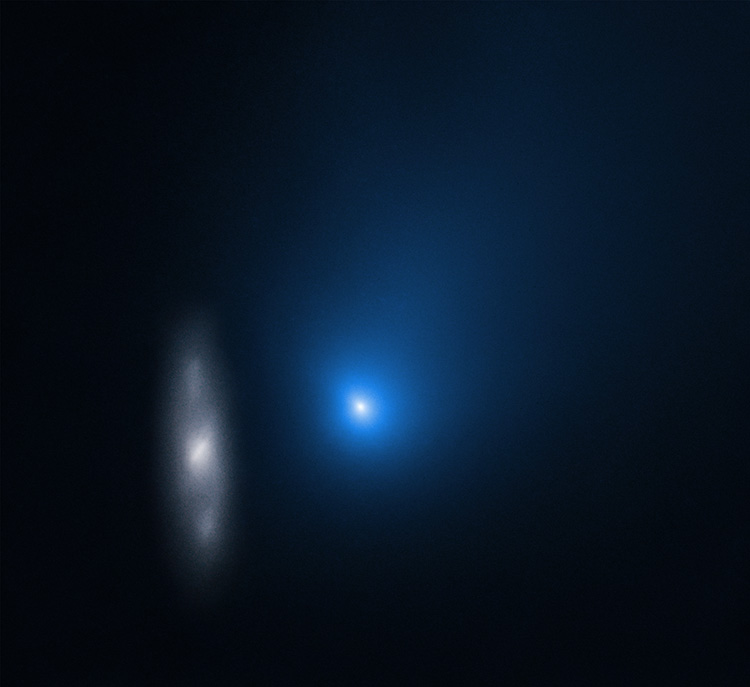 Borisov A fuzzy blue dot with a white center with a faint grayish galaxy to its left against a black background.