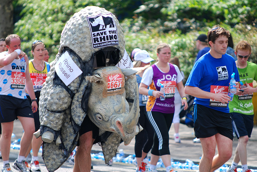 Save the rhino Photo of people in a run, including one person dressed up in a rhino costume. Signs read “Save the rhino.”
