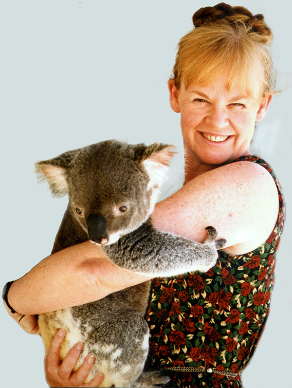 Jenny Graves plus koala A young woman with red hair in short-sleeved frock is holding a koala and smiling at the camera.