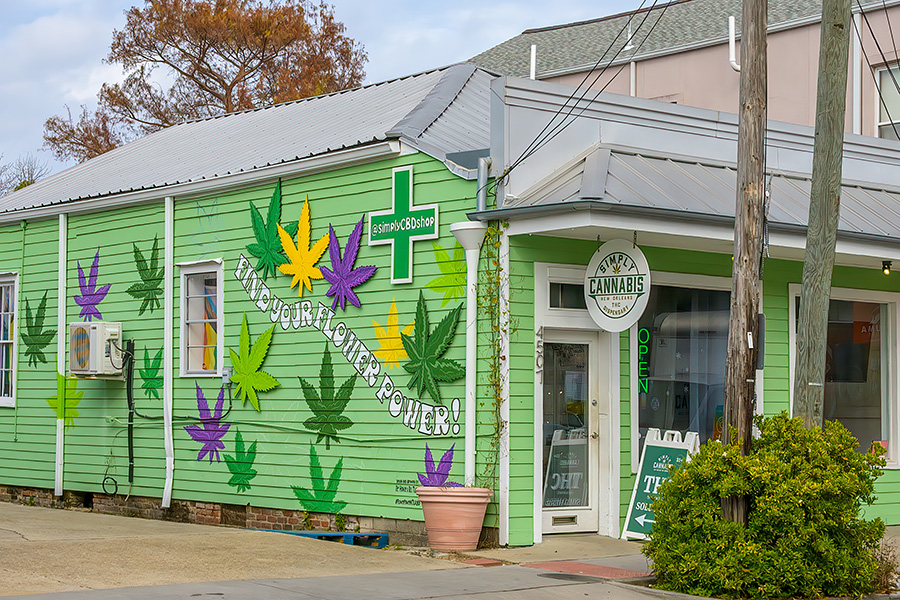 Medical marijuana Photo shows a brightly painted small building with marijuana leaves in yellow, purple and green decorating the side of the building. A green cross symbol and a front sign adorn the store.