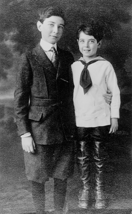 Brothers An old-fashioned black-and-white studio photo shows two boys, one younger in a sailor suit and long boots, the older taller one in a tweed suit.