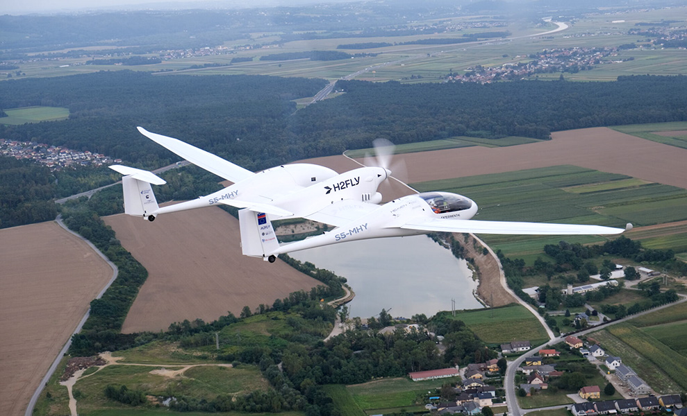 H2FLY A small white plane with “H2FLY” inscribed on its side flies above fields and houses.